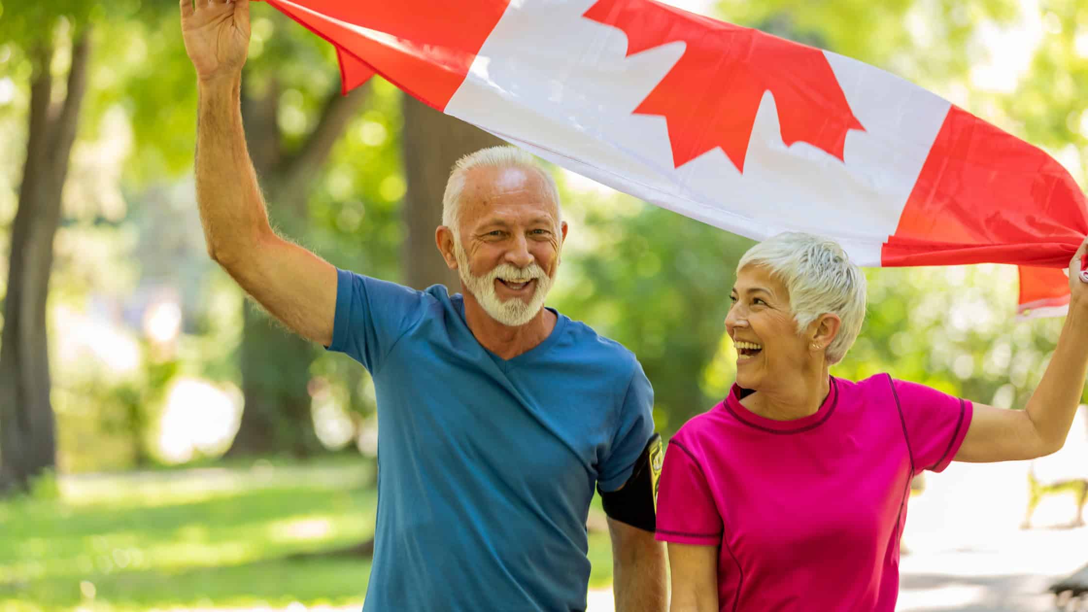 Two older adults waving Canadian flag