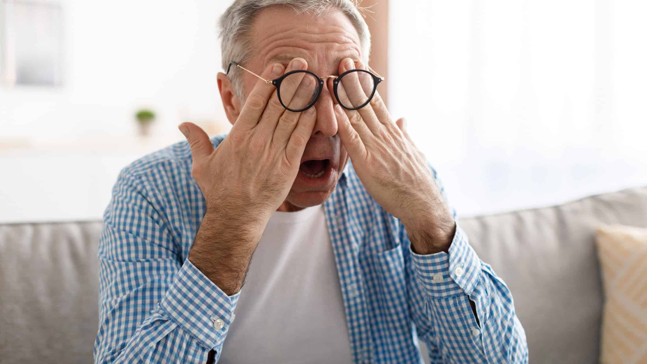 Older man rubbing his eyes