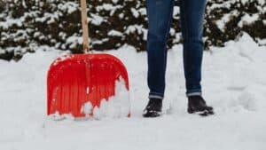 Man standing next to shovel in snow