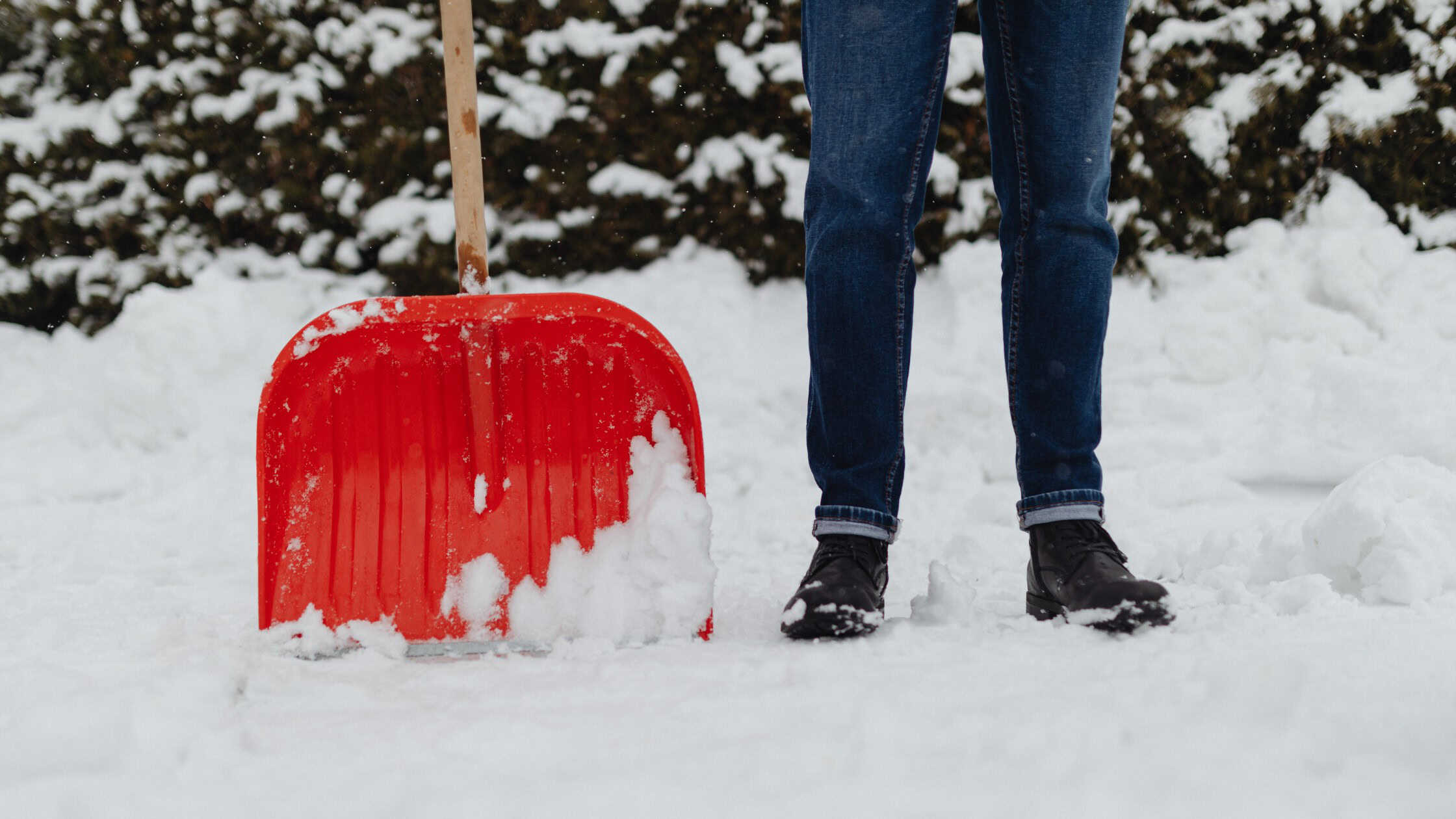 Man standing next to shovel in snow