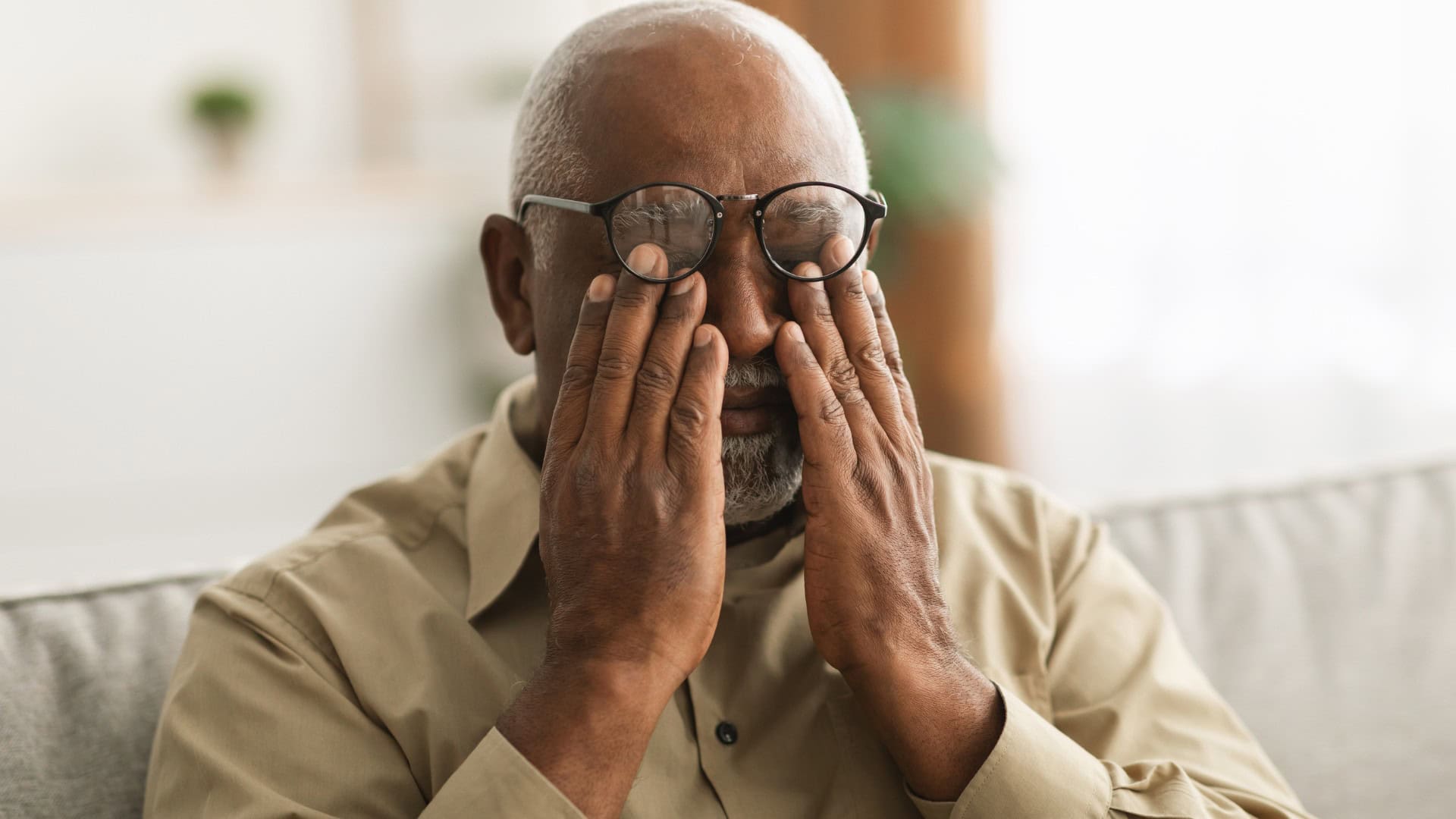 Stressed Older man with hands over eyes