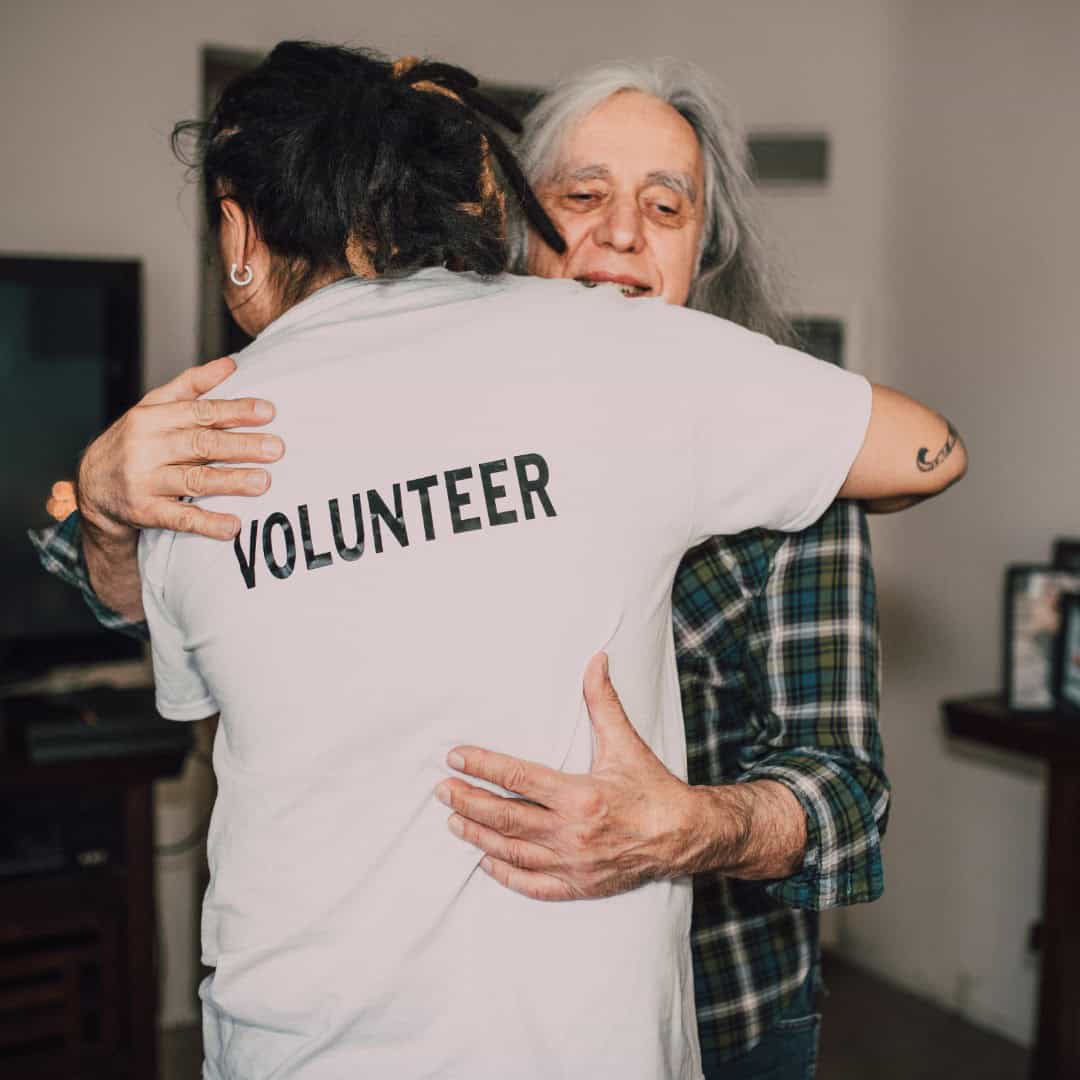 Volunteer hugging older person
